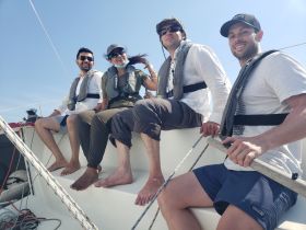 A cheerful group enjoys a sunny day sailing, showcasing camaraderie and adventure on the water.