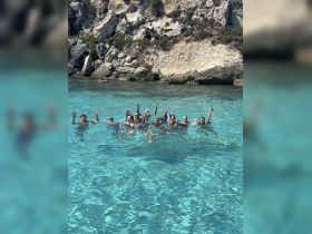 A lively group enjoys a refreshing swim in crystal-clear waters, celebrating their day on the water amidst stunning natural scenery.