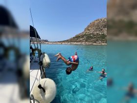 A child performs an impressive flip into the crystal-clear waters while others enjoy swimming nearby — a perfect moment of fun and adventure on a sunny day.
