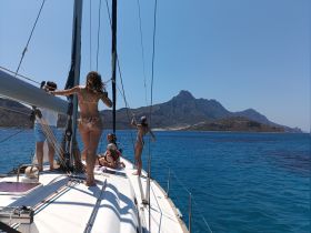 A lively group enjoys a sailing adventure on a sunny day, with stunning mountain views in the background — perfect for unforgettable moments on the water.
