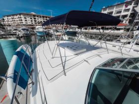 A close-up view of a yacht's deck and canopy, docked in a marina, showcasing its sleek design and surrounding boats.