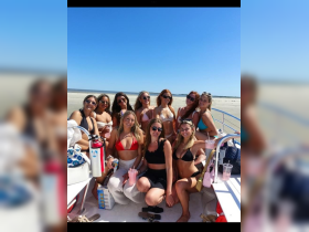 A lively group of friends enjoys a fun day on the boat, celebrating with drinks and sunshine — perfect for a beach party atmosphere.