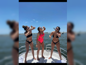 Three friends enjoy a fun moment on a boat, celebrating with drinks under the sun — perfect for summer parties and memorable outings on the water.