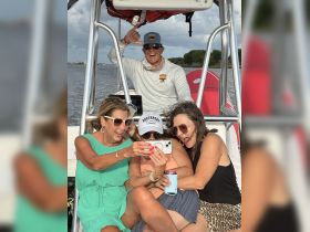 A lively group of friends enjoys a fun moment on a boat, capturing memories together with smiles and laughter — perfect for a day out on the water.