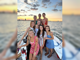 A joyful group of friends poses for a photo on a boat at sunset, celebrating their time together on the water — perfect for memorable outings and gatherings.