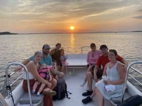 A joyful family gathers on a boat at sunset, creating cherished memories during their scenic outing on the water.