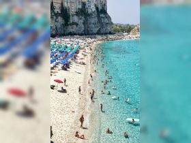A vibrant beach scene filled with sunbathers and swimmers enjoying the clear turquoise waters, perfect for a summer getaway.