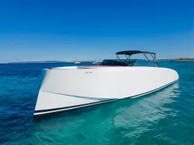 A sleek speedboat glides through crystal-clear waters, showcasing its modern design against a stunning blue sky — perfect for thrilling day trips on the water.