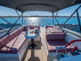 A beautifully designed interior of a boat featuring comfortable seating and a stylish table set with drinks and snacks, perfect for relaxing on the water.
