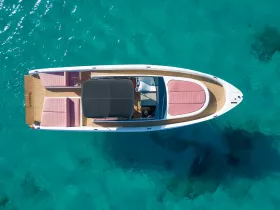 A stunning aerial view of a sleek speedboat cruising through crystal-clear waters, showcasing its elegant design and inviting seating areas.