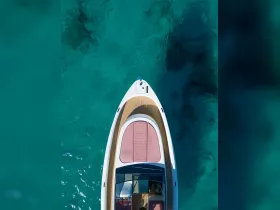 A stunning aerial view of a sleek yacht gliding over crystal-clear waters, showcasing its elegant design and inviting deck space.
