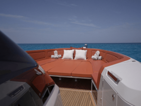 A stylish lounge area on a boat featuring plush seating and decorative pillows, perfect for relaxing while enjoying the ocean views.