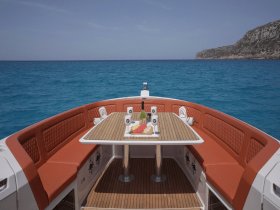 A beautifully arranged dining area on a boat, featuring comfortable seating and a table set with refreshments, perfect for enjoying meals while cruising on the open water.