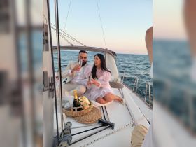 A couple enjoys a romantic moment on a yacht, toasting with champagne as the sun sets over the ocean — perfect for special celebrations or intimate getaways.