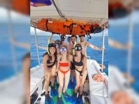 A cheerful group prepares for snorkeling on a boat, showcasing the excitement of underwater adventures in a tropical setting.