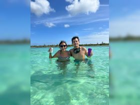 A couple enjoys a refreshing swim in crystal-clear waters, celebrating their day with drinks in hand — a perfect moment for fun and relaxation on the water.