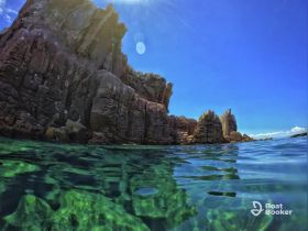 A stunning view of rocky coastline and crystal-clear waters, perfect for showcasing the natural beauty of the area — ideal for eco tours and scenic boat trips.