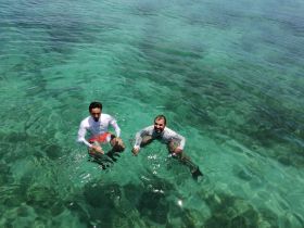 Two friends enjoy a refreshing swim in crystal-clear waters, capturing the essence of fun and relaxation during their boating adventure.