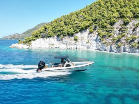A sleek speedboat glides through crystal-clear turquoise waters, showcasing the stunning coastal scenery — perfect for exploring hidden coves and enjoying a day on the water.