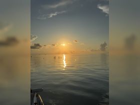A serene sunset view over calm waters, with reflections shimmering on the surface — perfect for capturing the beauty of a tranquil evening at sea.