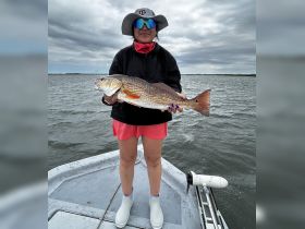 A young girl proudly displays her catch while fishing on a boat, showcasing the thrill of a successful fishing trip.