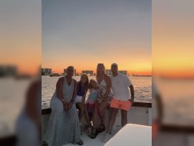 A joyful family poses together on a boat at sunset, capturing a memorable moment during their boating adventure.