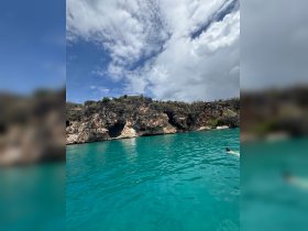 A swimmer enjoys the vibrant turquoise waters near a stunning rocky coastline, showcasing the beauty of a tropical adventure.