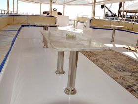 Interior view of a spacious boat cabin featuring comfortable seating and a marble table, perfect for relaxing or dining while on the water.