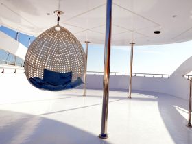 A stylish hanging chair in the lounge area of a boat, perfect for relaxing and enjoying the views while cruising on the water.