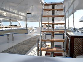 Interior view of a spacious boat cabin featuring comfortable seating and a staircase leading to the upper deck, ideal for relaxing and enjoying the journey.