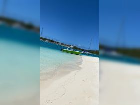A vibrant speedboat is docked in crystal-clear turquoise waters, surrounded by a picturesque beach — an ideal setting for a day of relaxation and adventure.