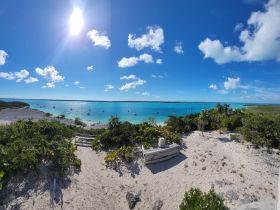 A stunning panoramic view of turquoise waters and sailboats anchored along a picturesque coastline, perfect for showcasing the beauty of island destinations.