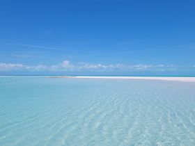 A stunning view of a secluded beach with crystal-clear turquoise waters and a bright blue sky, perfect for showcasing the beauty of tropical destinations.