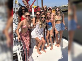 A lively group of friends poses for a fun photo on the deck of a yacht, perfect for celebrating special occasions or enjoying a day out on the water.
