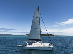 A stunning aerial view of a sailboat navigating through crystal-clear waters, showcasing the beauty of sailing adventures in tropical destinations.
