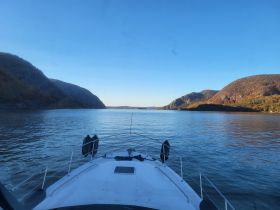 A stunning view from the front of a boat navigating through a serene waterway, flanked by picturesque hills, perfect for exploring nature's beauty.