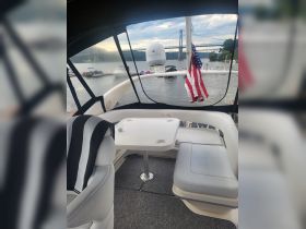A cozy interior view of a Sea Ray boat featuring comfortable seating and a table, perfect for relaxing while enjoying the scenic waterfront.