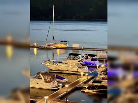 A serene view of various boats docked at a marina, illuminated by soft lights reflecting on the calm water — perfect for evening outings and boat rentals.