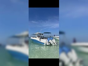 Two crew members stand on the deck of a boat anchored in clear waters, ready for an exciting day on the ocean.