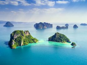 A stunning aerial view of lush green islands surrounded by crystal-clear waters, showcasing the breathtaking beauty of coastal landscapes — perfect for island hopping adventures.