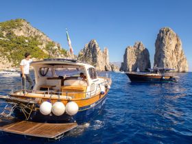 A scenic view of boats navigating near stunning rock formations, capturing the essence of a perfect day on the water in Capri.