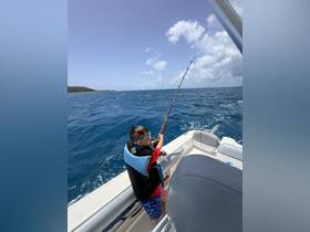 A young boy enjoys fishing from the deck of a boat, showcasing the excitement of a day on the water. Perfect for family fishing trips and ocean adventures.