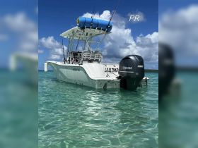 A sleek Sea Fox speedboat named 'La Ultima' anchored in crystal-clear waters, showcasing its stylish design against a backdrop of blue skies and fluffy clouds.