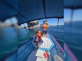 A family enjoys a boat ride while exploring scenic rock formations, all wearing life jackets for safety — a perfect adventure on the water.