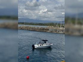 A group of anglers prepares for a fishing adventure aboard a boat, set against a scenic coastal backdrop.