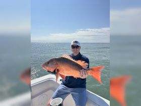 A proud angler displays a vibrant snapper catch while enjoying a day on the water — a perfect moment for fishing enthusiasts.
