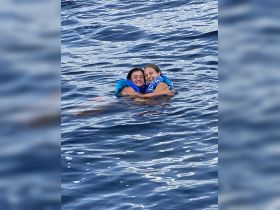 Two girls enjoy a joyful moment swimming together in the open water, showcasing the fun and excitement of a day on the boat.