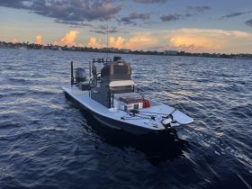 A sleek speedboat glides through the water under a colorful sunset, showcasing its design and functionality — perfect for fishing or leisure outings.