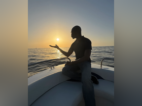 A man enjoys a stunning sunset on a boat, creating a picturesque silhouette against the vibrant sky — a perfect moment for relaxation and reflection on the water.