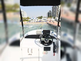 A detailed view of the helm and console area inside a boat, showcasing the steering wheel and navigation equipment — perfect for those looking to explore the waters.
